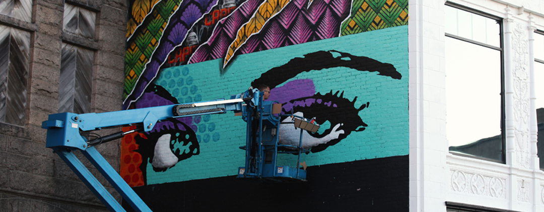 Image of Rene Gagnon on a manlift paintg a mural