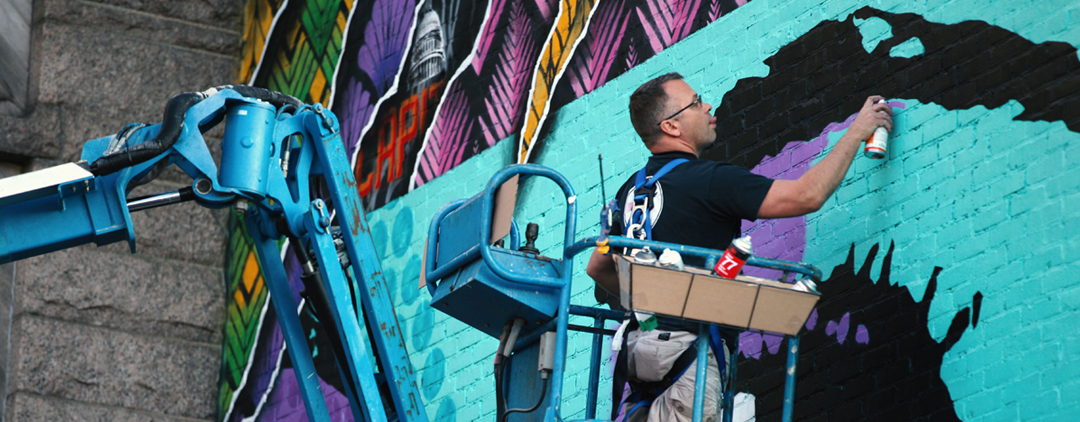 Close up image of Rene Gagnon painting a mural